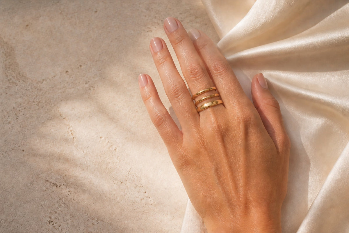 Editorial photograph of three separate gold-tone rings stacked with space between each band