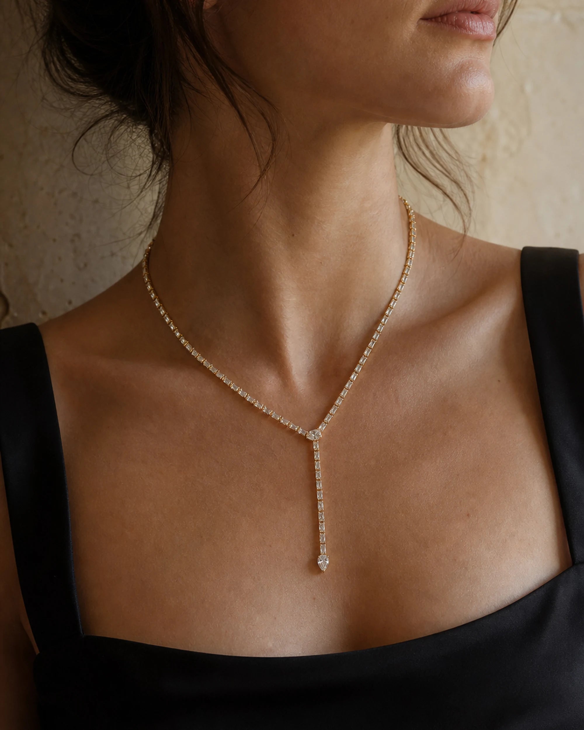 Close collarbone view of the Liora Gold Crystal Y-Drop Necklace with a black square-neck top