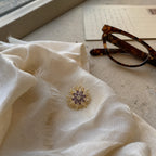 Purple and Gold Meri Magnetic Bloom Brooch in a silk scarf travel still life