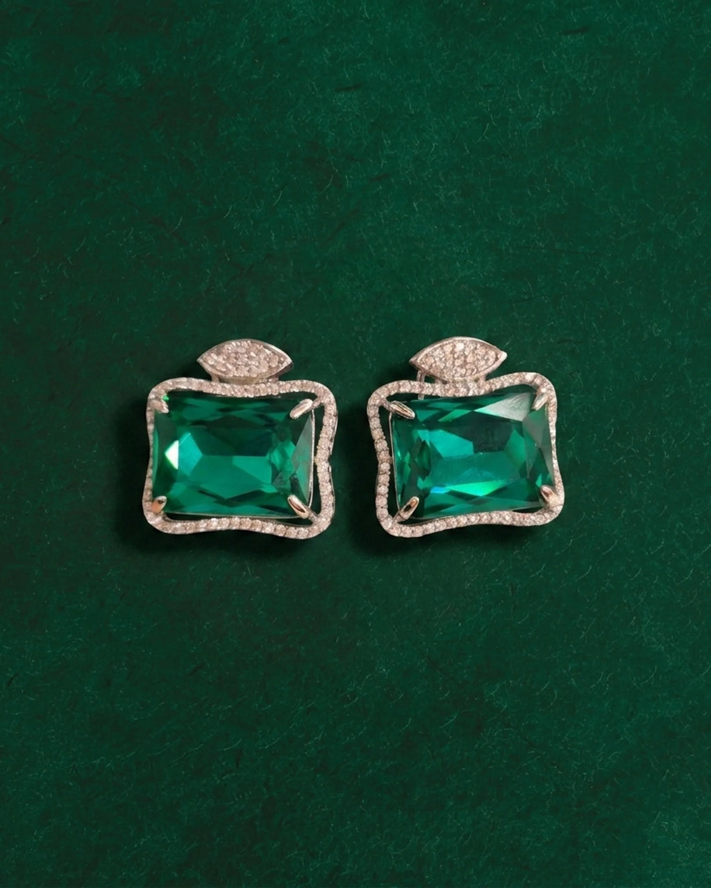 Pair of Ruutu green statement earrings on a deep green surface