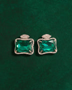 Pair of Ruutu green statement earrings on a deep green surface