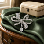 Sylvi Crystal Ribbon Brooch displayed on green silk
