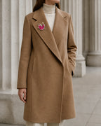 Wide view of Aila at true scale on a camel coat lapel