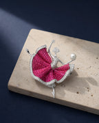 Aila fuchsia ballerina brooch resting on ivory travertine in an original TUUGLOW still life