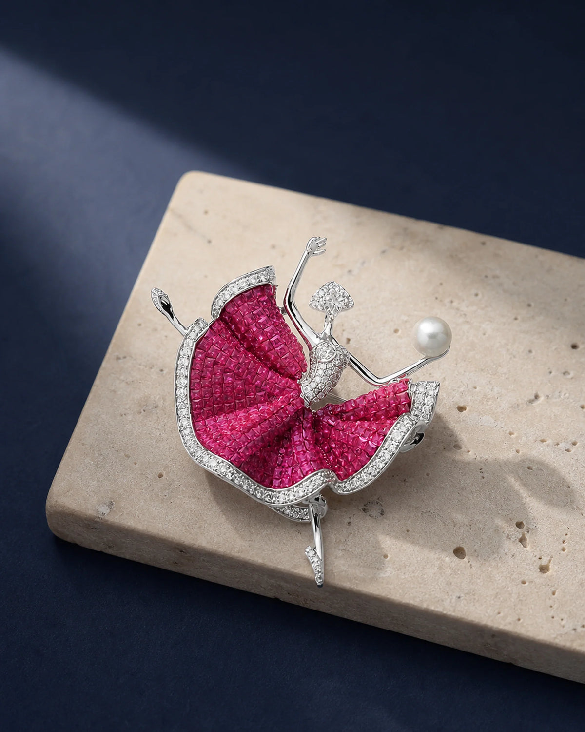 Aila fuchsia ballerina brooch resting on ivory travertine in an original TUUGLOW still life
