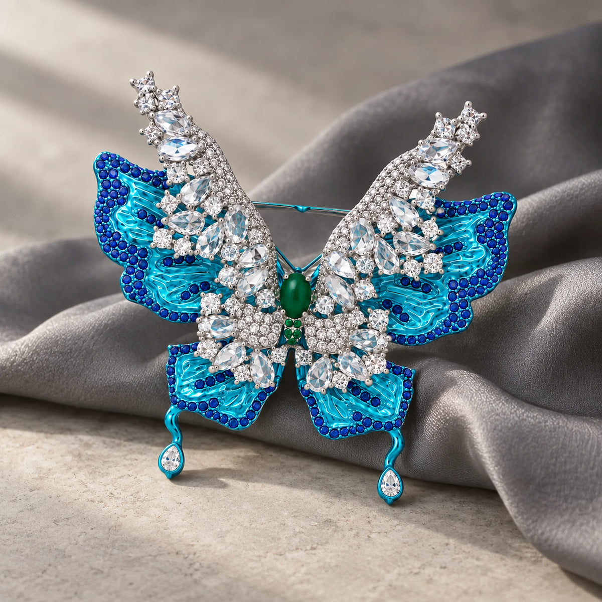 Airi layered butterfly brooch supported by folded gray silk on a pale stone surface.