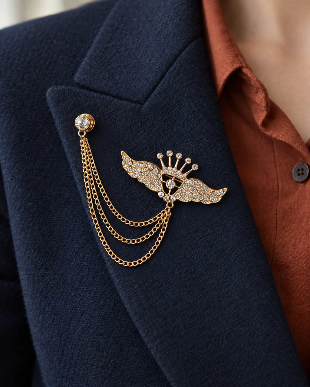 Alar Winged Crown Lapel Chain Brooch in gold-tone finish; close wearing view on a structured lapel