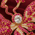 Rose-pink stones, clear accents and gold-plated veins follow the sculpted wings.