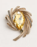 Astra Orbit Crystal Brooch with a champagne pear-cut crystal on a warm grey studio surface