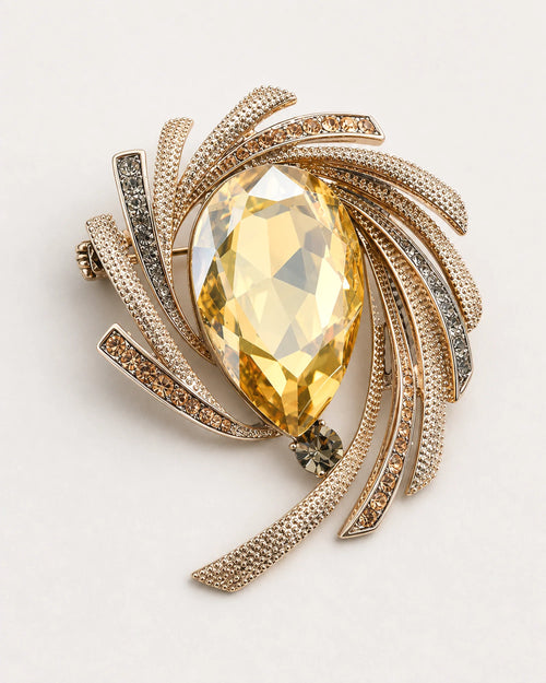 Astra Orbit Crystal Brooch with a champagne pear-cut crystal on a warm grey studio surface