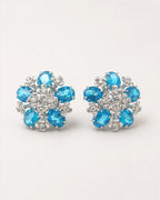 Azura Blue Glass Floral Omega-Back Earrings on an exact #F0EBE9 studio background with natural contact shadows.