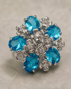 Macro view of the Azura earring's five aqua-blue faceted glass stones and silver-tone floral setting.