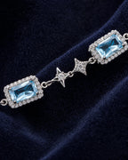 Macro view of a rectangular blue zircon center, clear halo and four-point star link on the Celeste bracelet.