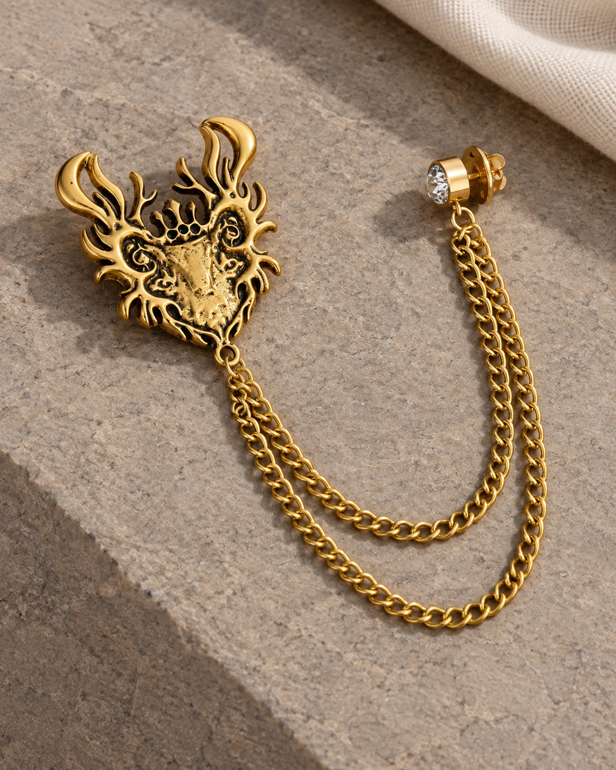Draka Horned Crest Lapel Chain Brooch in gold-tone finish; complete still-life drape