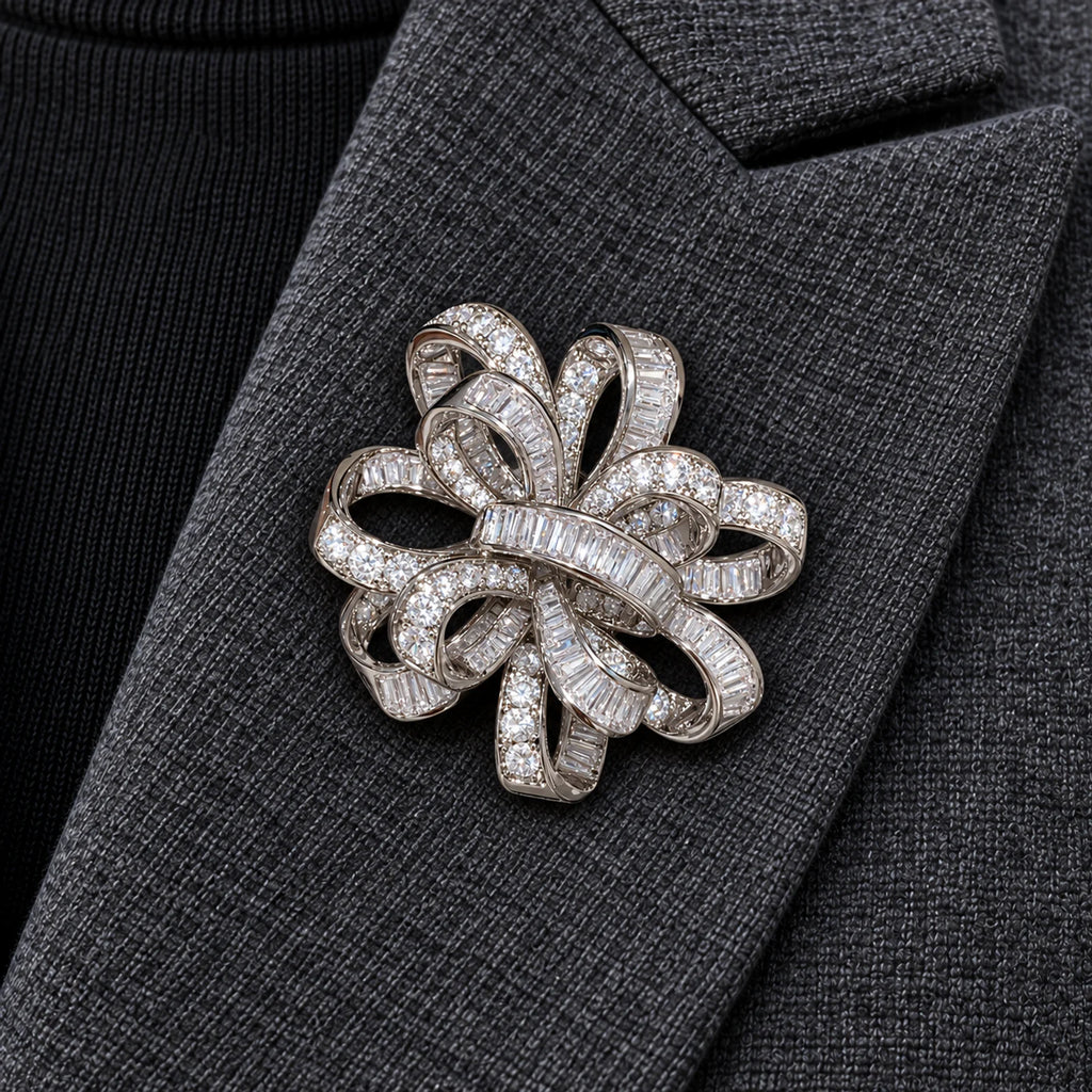 Close centered view of the silver-tone Elva ribbon rosette brooch pinned inside a charcoal wool lapel