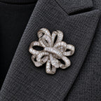 Close centered view of the silver-tone Elva ribbon rosette brooch pinned inside a charcoal wool lapel