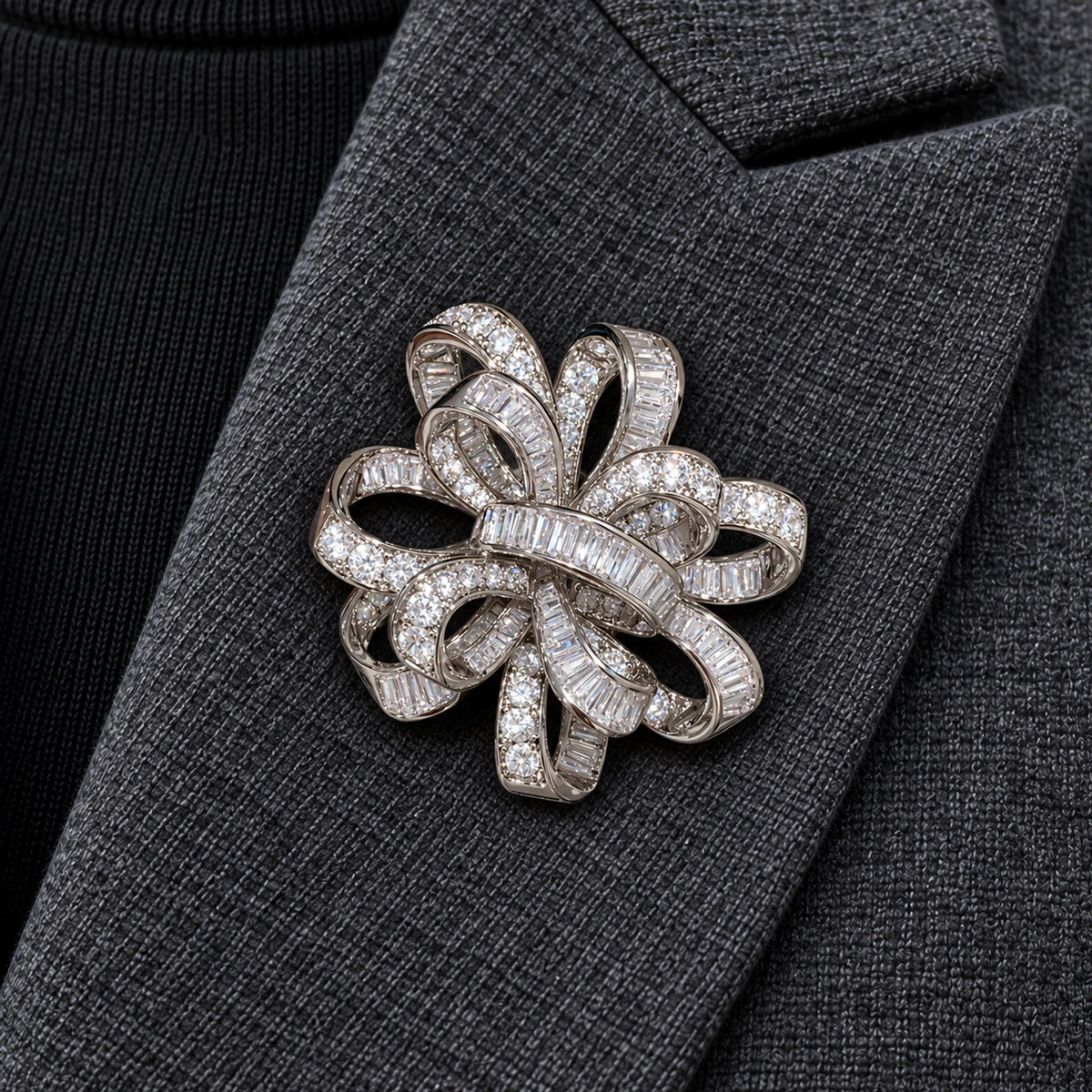 Close centered view of the silver-tone Elva ribbon rosette brooch pinned inside a charcoal wool lapel