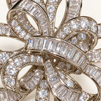 Close detail of clear baguette and round zircon stones across the interwoven ribbon bands