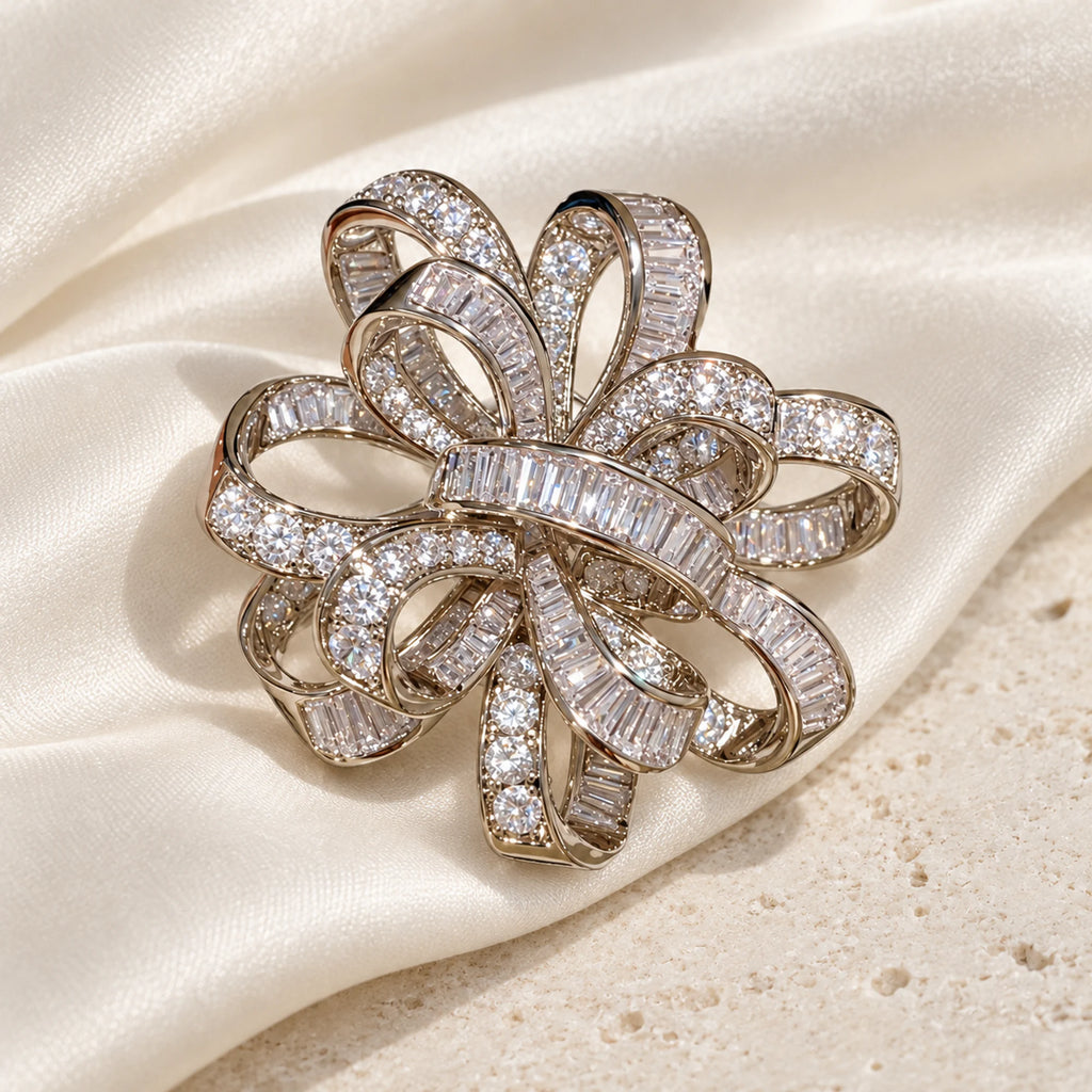 Silver-tone Elva ribbon rosette brooch resting on ivory silk over pale limestone