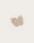 Eveli Marquise Crystal Butterfly Brooch on a warm #F0EBE9 studio background with a natural contact shadow