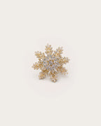 Halla Eight-Point Crystal Snowflake Brooch on a warm #F0EBE9 studio background with a natural contact shadow