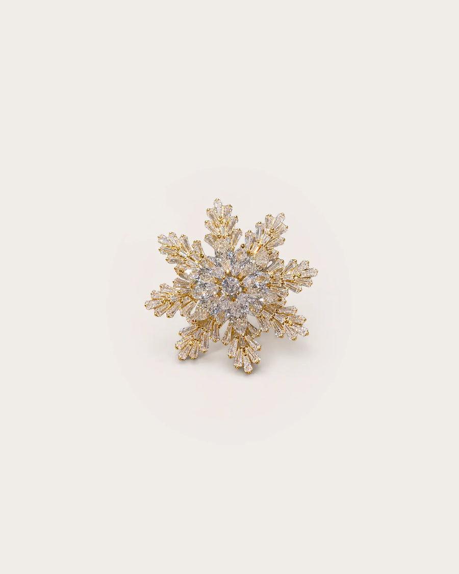 Halla Eight-Point Crystal Snowflake Brooch on a warm #F0EBE9 studio background with a natural contact shadow