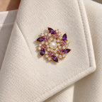 The pearl-centred purple flower sits entirely within a broad ivory folded lapel.