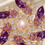Purple marquise zircon and clear round settings circle a lustrous freshwater pearl.