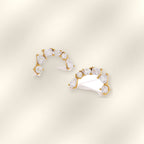 Pair of Ilo Smile Pave Stud Earrings on soft satin background