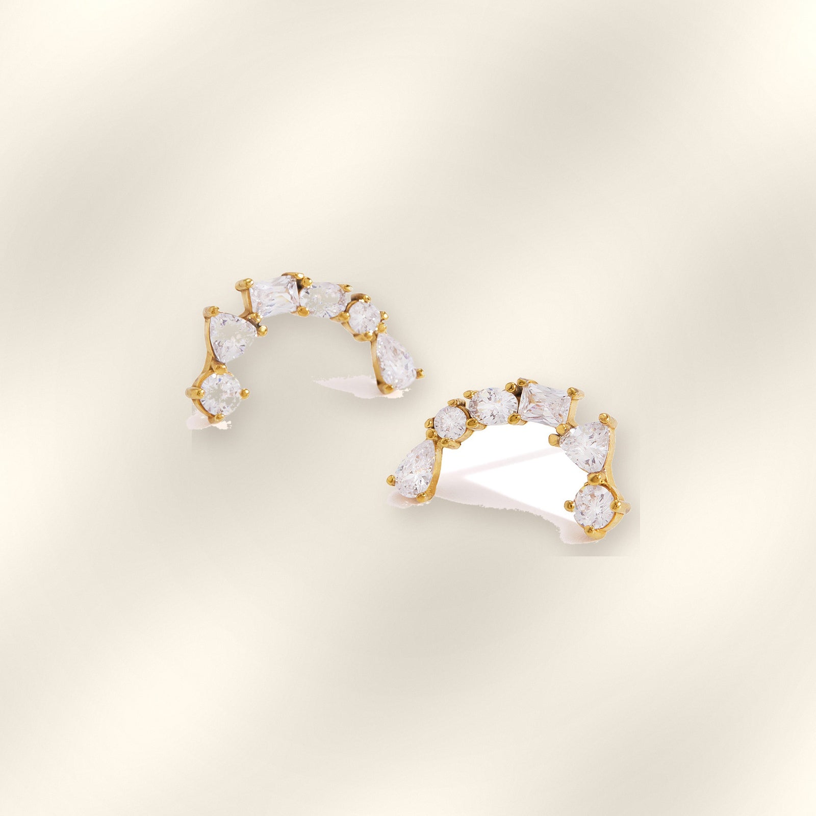 Pair of Ilo Smile Pave Stud Earrings on soft satin background