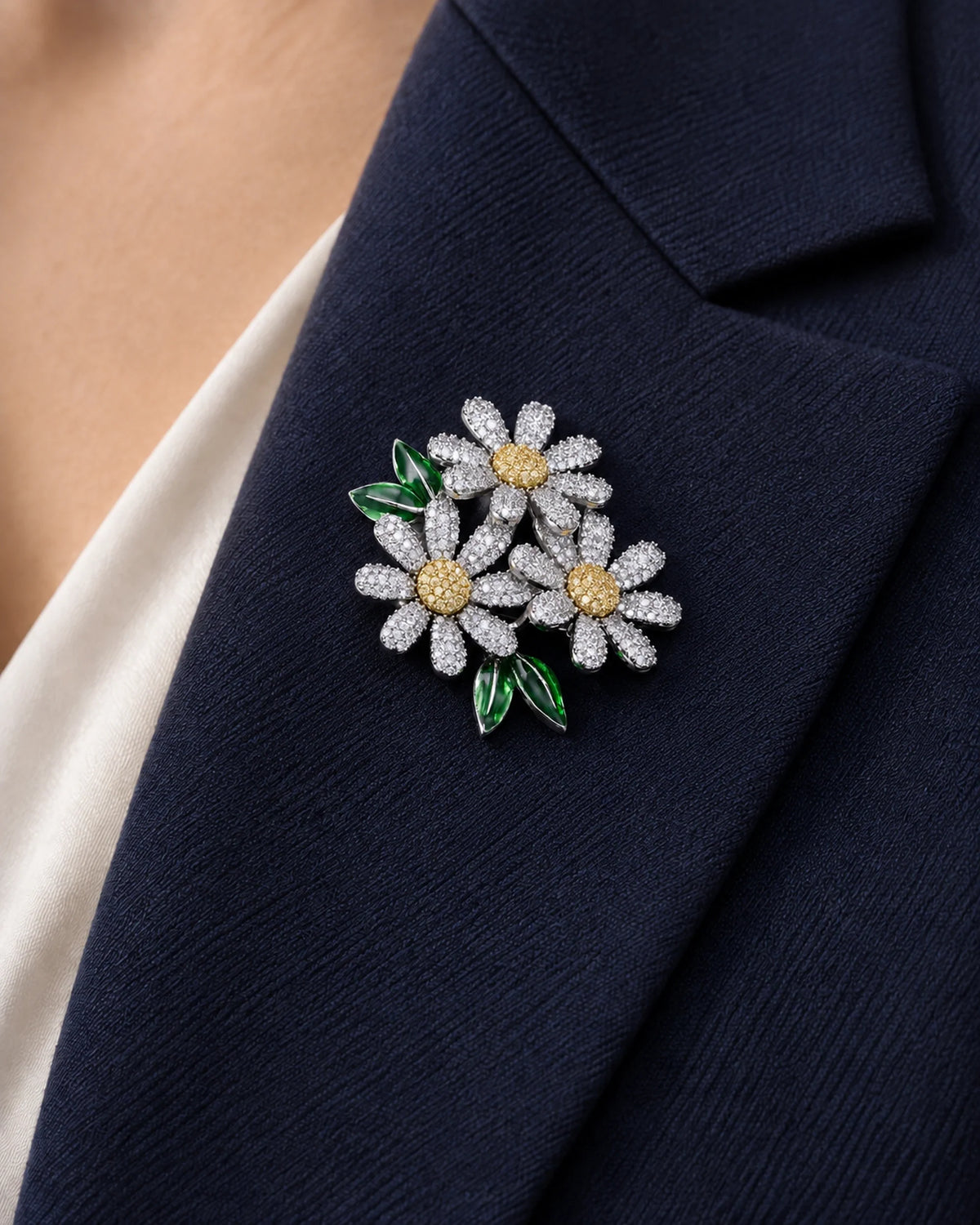 Ilona silver-tone daisy brooch with visible petal sidewalls and green leaves on a navy lapel