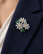 Ilona silver-tone daisy brooch with visible petal sidewalls and green leaves on a navy lapel