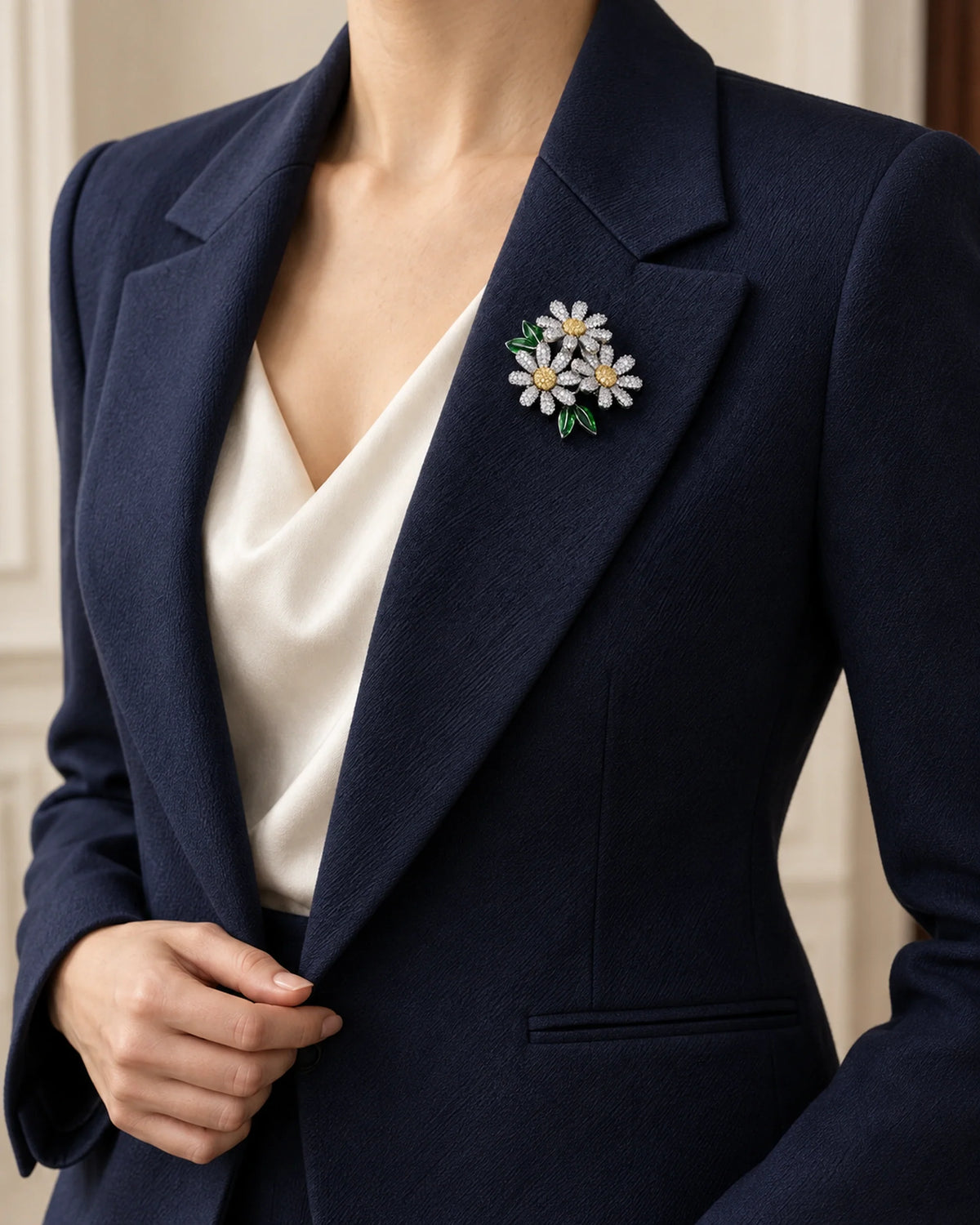 Ilona silver-tone daisy trio brooch on a navy blazer with a softly draped ivory top