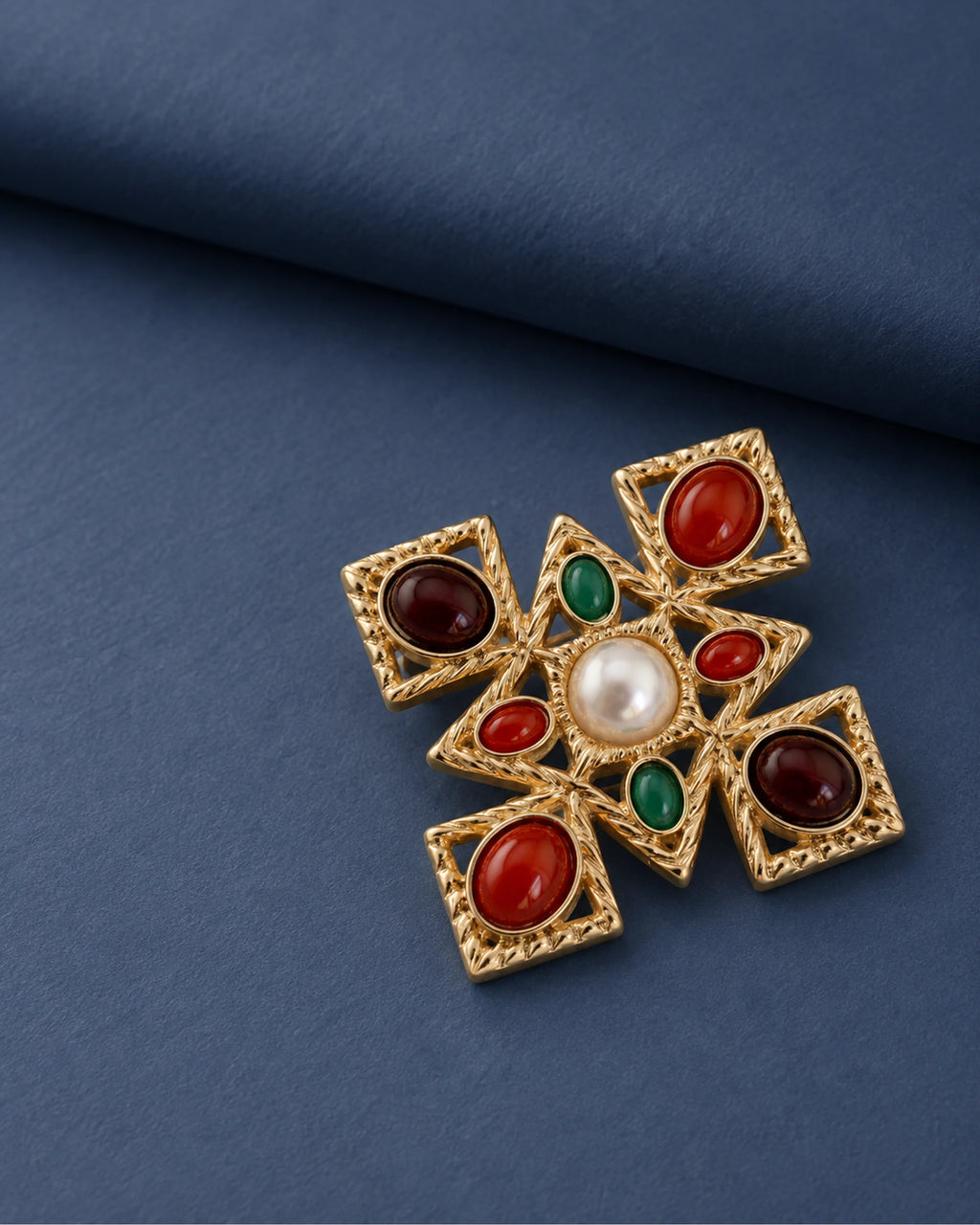 Ivar Red and Green Cross Brooch — front display on folded slate-blue paper