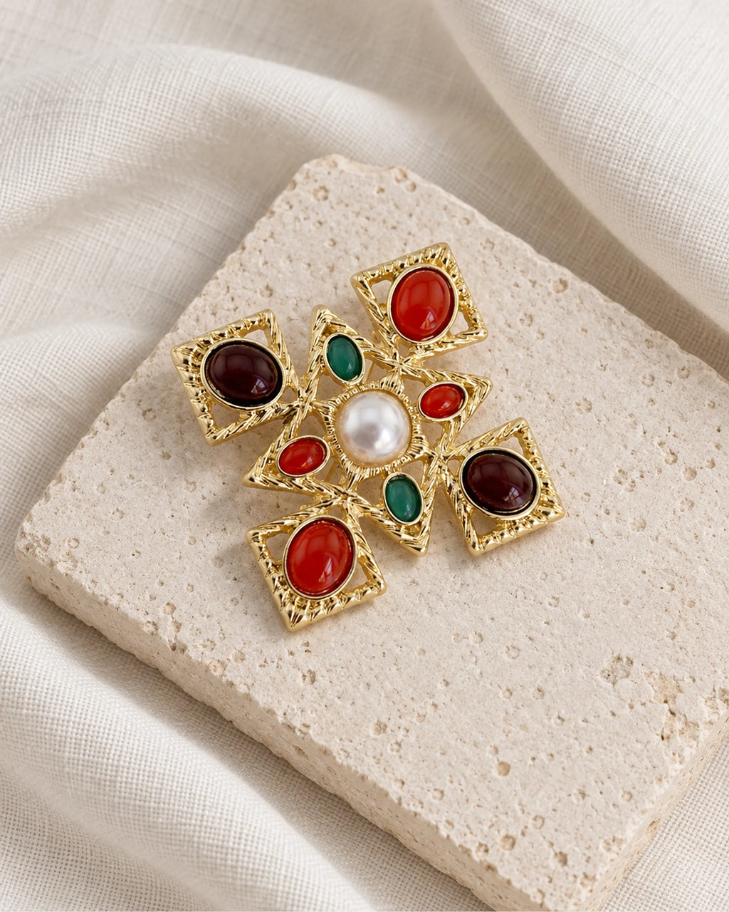 Ivar Red and Green Cross Brooch — front view on a stone tile and ivory linen