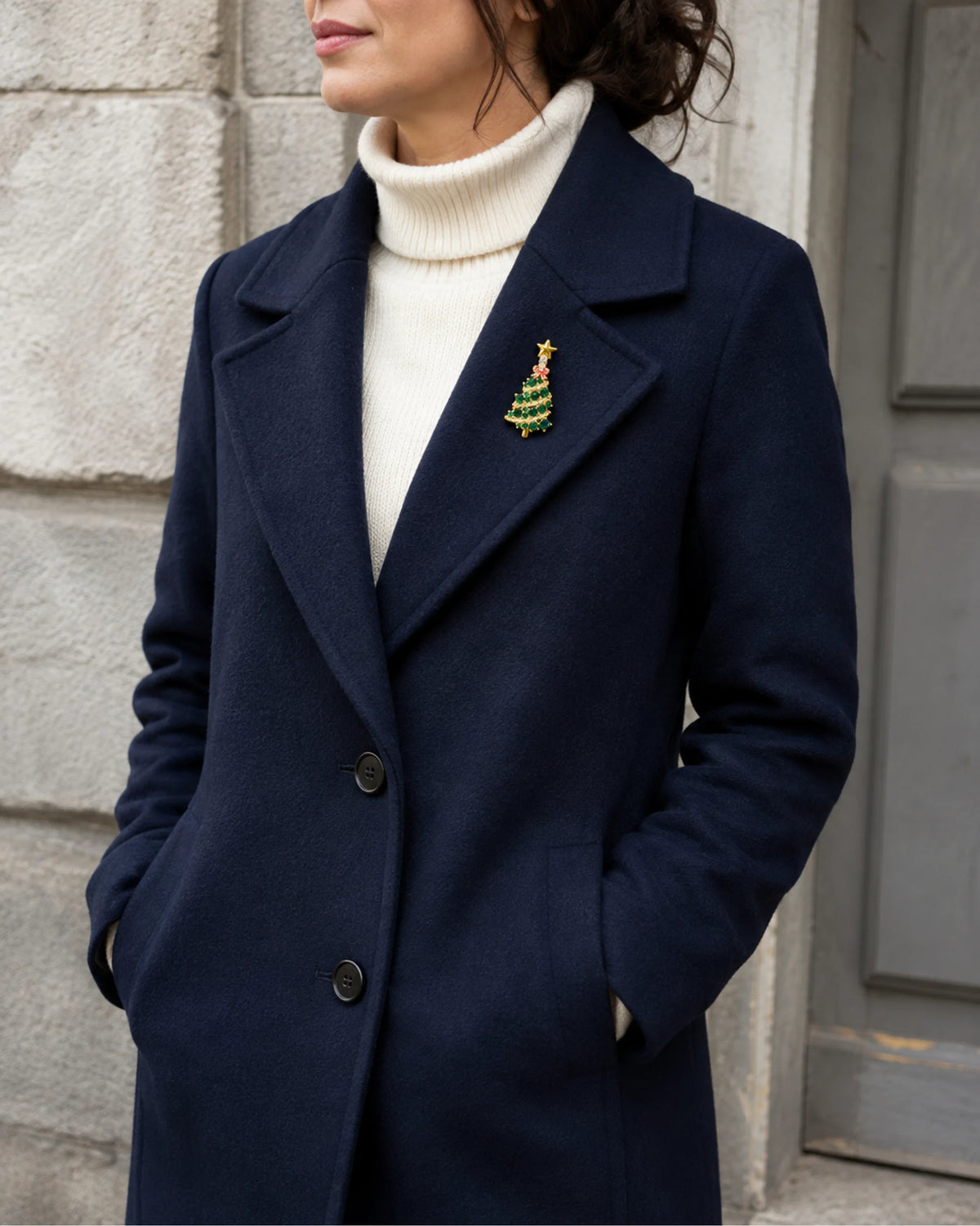 Green tree brooch worn on a navy wool coat above an ivory rollneck.