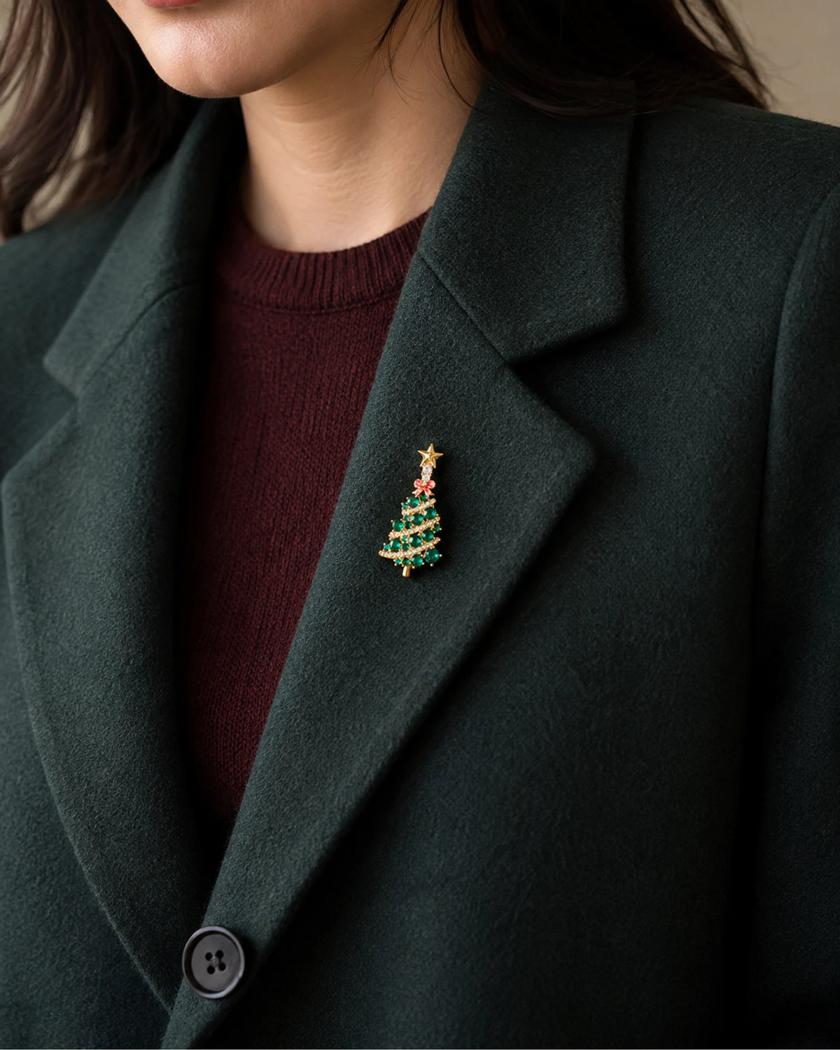Small green Christmas tree brooch pinned inside a forest-green wool blazer lapel.