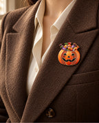 The orange candy pumpkin sits inside a chocolate lapel over a cream shirt.