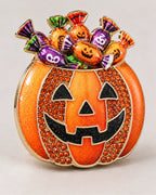 Wrapped-candy motifs rise above the black pumpkin face and orange crystal-set sides.