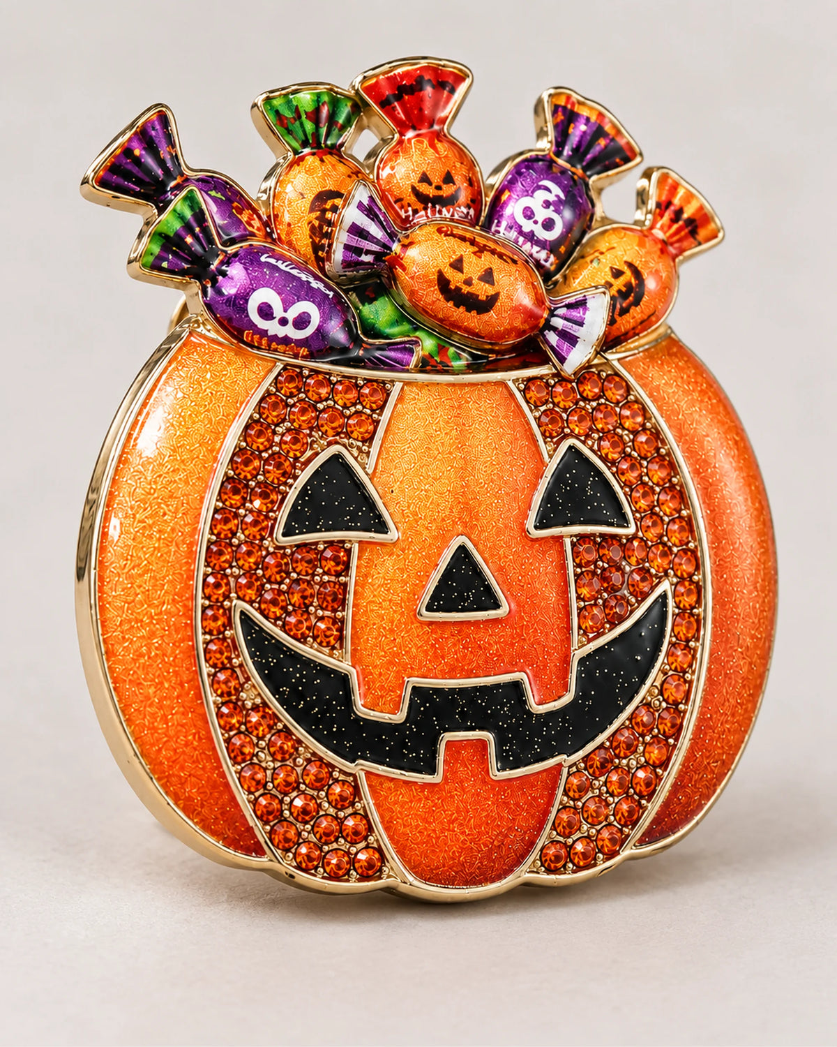 Wrapped-candy motifs rise above the black pumpkin face and orange crystal-set sides.