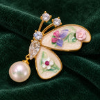 Kielo’s two floral wings and pearl-look drop displayed on forest-green velvet.