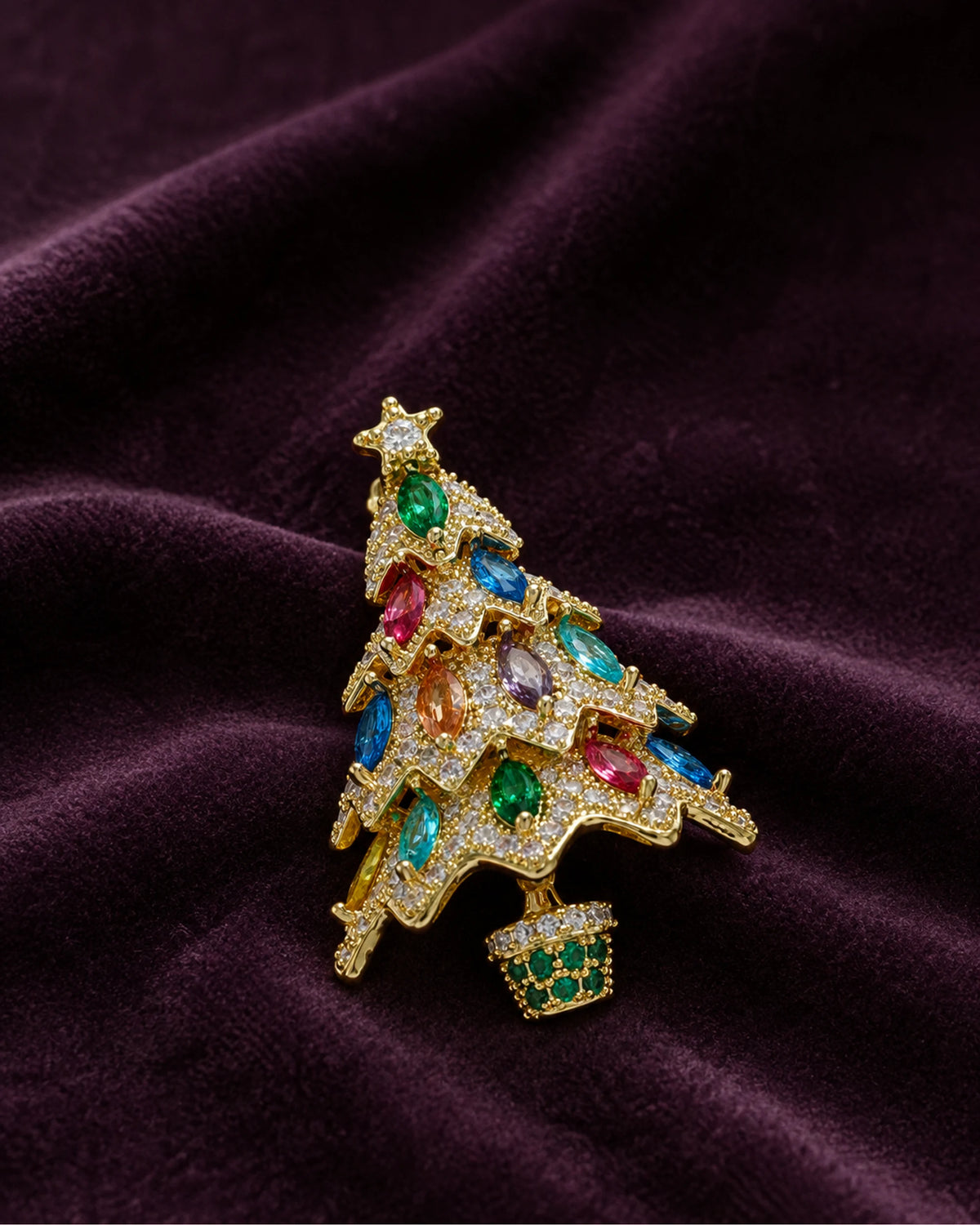 Multicolor Kuusi brooch resting on deep plum fabric.