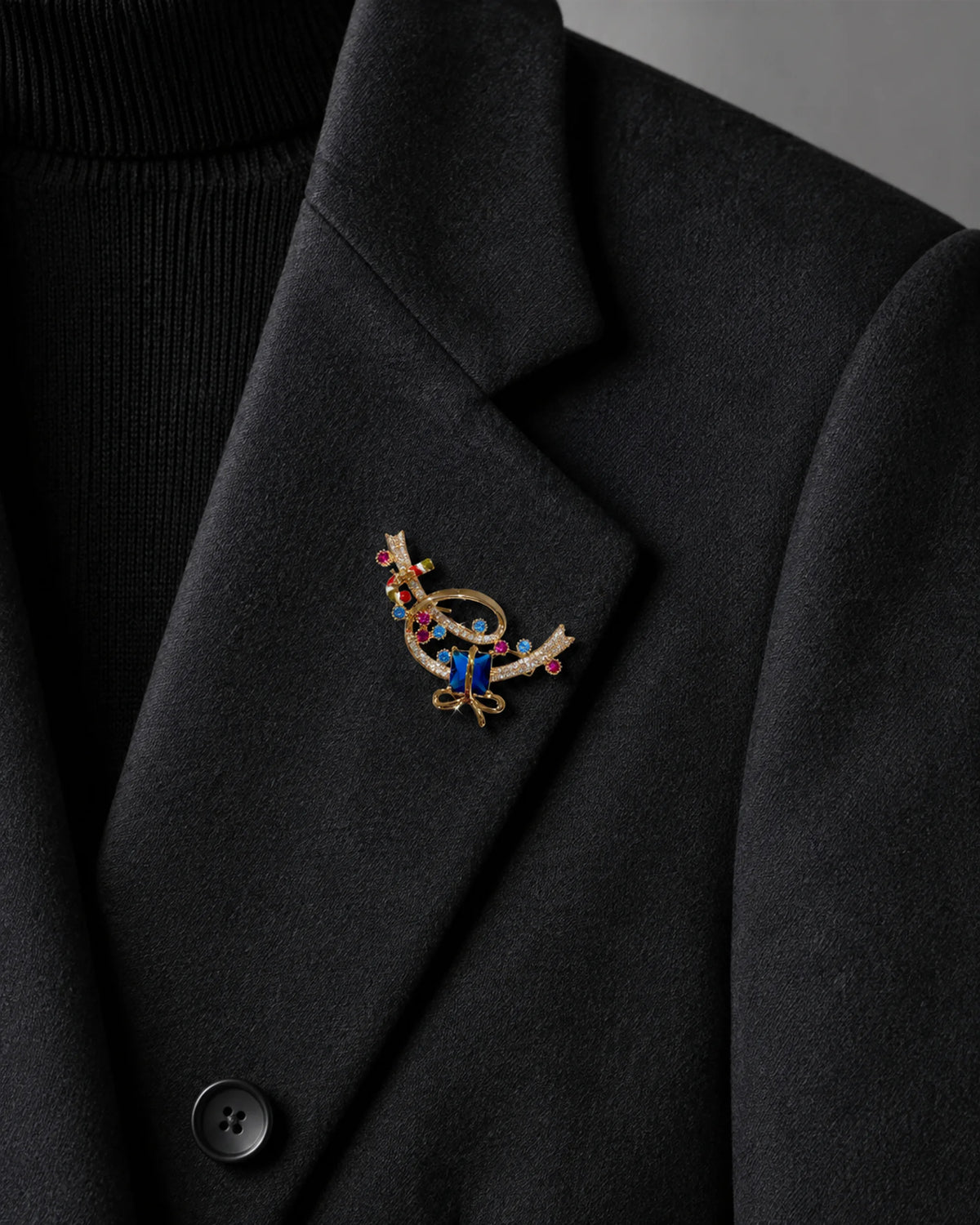 Close view of the small blue gift ribbon brooch pinned within a charcoal blazer lapel.