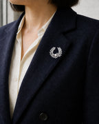 Laurea silver freshwater pearl wreath brooch fastened within a navy blazer lapel.