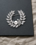 Laurea silver freshwater pearl leaf wreath brooch resting on a charcoal slate surface.