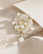 Linnea Pearl Shell Flower Brooch resting on pale travertine, ivory paper and champagne silk