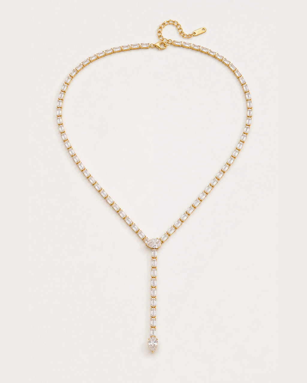 Liora Gold Crystal Y-Drop Necklace resting on a soft #F0EBE9 studio surface