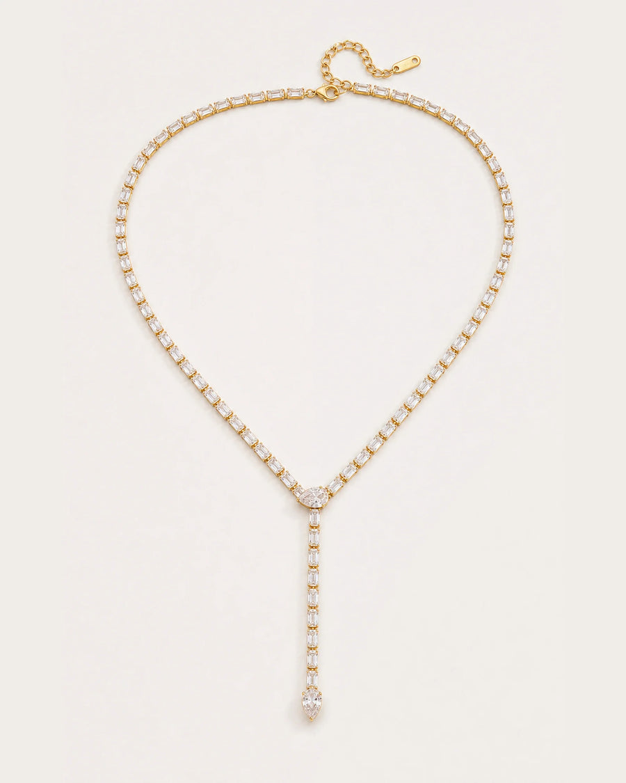 Liora Gold Crystal Y-Drop Necklace resting on a soft #F0EBE9 studio surface