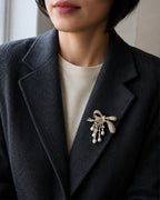 Lova Freshwater Pearl Bow Brooch pinned within a charcoal herringbone blazer lapel