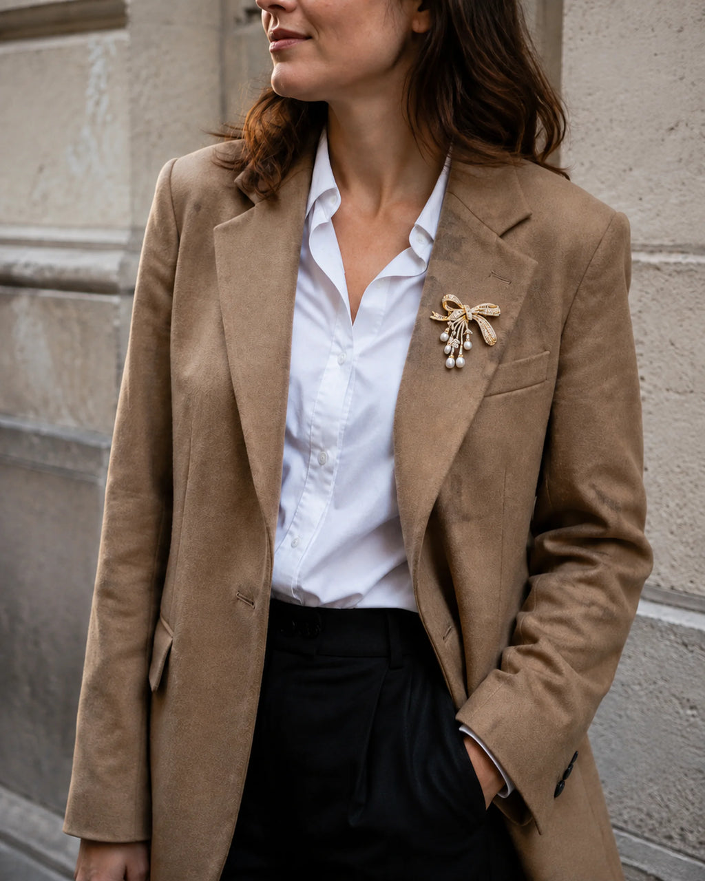 Gold-tone freshwater pearl bow brooch styled on a camel blazer with a white shirt